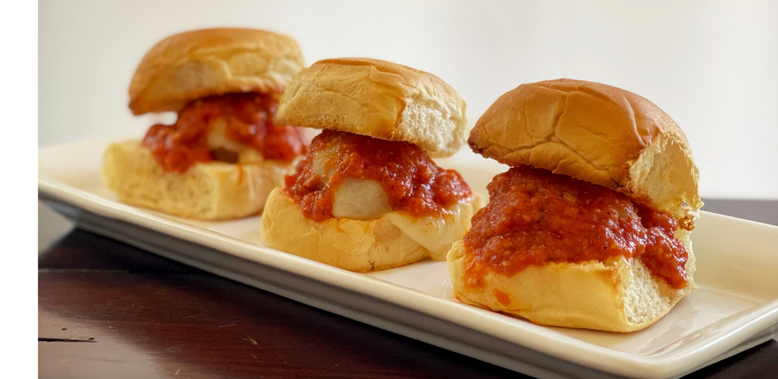 3 mini chicken sliders side by side drenched in Heatily red sauce on the inside